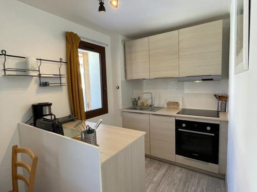 - une cuisine avec un comptoir et une cuisinière four supérieur dans l'établissement Appartement cosy 4 pers, proche télécentre, balcon - L'Alpe d'Huez - FR-1-405-25, à L'Alpe-d'Huez