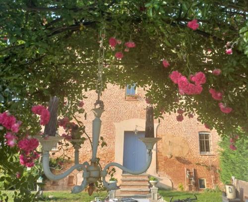 a building with a blue door and some pink roses at La Boheme in Villanova dʼAsti