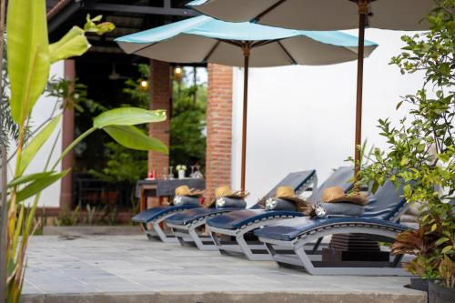 a row of tables with umbrellas on a patio at Atoh's Maison in Siem Reap