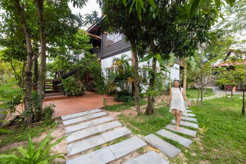 a woman walking down a stone walkway in front of a house at Atoh's Maison in Siem Reap
