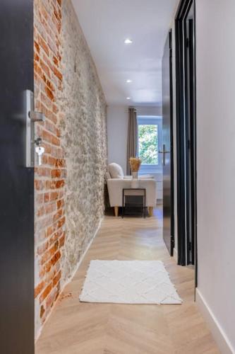 a hallway with a brick wall and a white rug at L'Écrin De L'Hyper Centre in La Rochelle