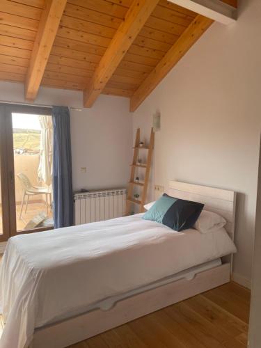 1 dormitorio con cama blanca y techo de madera en Ático en la Antigua Casa de Correos, en Molina de Aragón