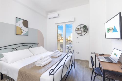 Schlafzimmer mit einem Bett, einem Schreibtisch und einem Laptop in der Unterkunft Quarzo. Modern Rooms in Cagliari