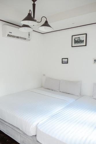two beds in a room with white walls at Sidewalk Boutique Hotel in Ko Samed