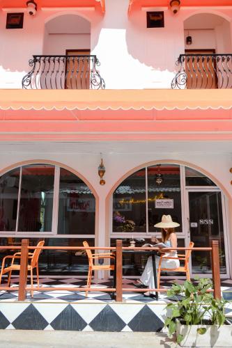 a woman sitting at a table in front of a building at Sidewalk Boutique Hotel in Ko Samed