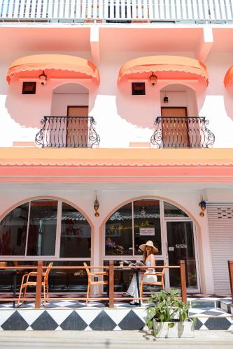 a woman sitting at a table in front of a building at Sidewalk Boutique Hotel in Ko Samed