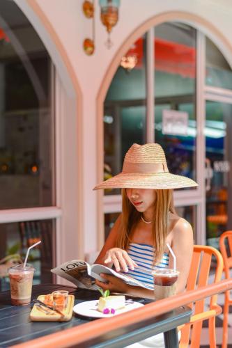a woman in a straw hat sitting at a table at Sidewalk Boutique Hotel in Ko Samed