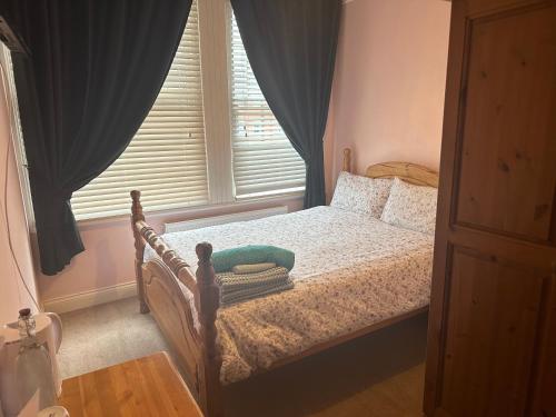 a bedroom with a bed and a window with blue curtains at 287 Green Lanes in London