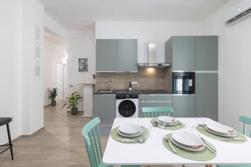 a kitchen and dining room with a white table and chairs at Quarzo. Modern Rooms in Cagliari