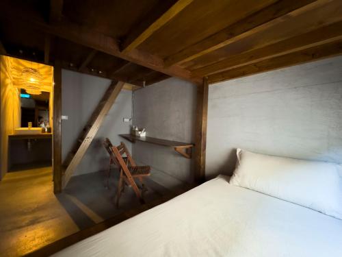 a bedroom with a white bed and a chair at DH House in Donghe