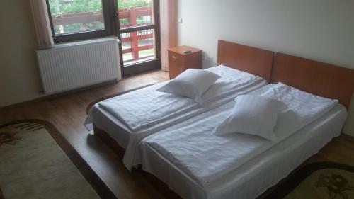 a bedroom with a bed with white sheets and pillows at Pensiunea Adi Sapinta in Săpânța