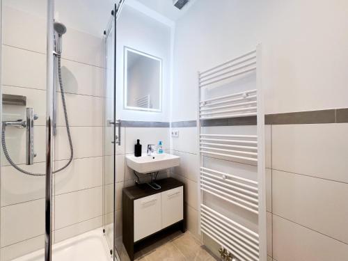 a white bathroom with a sink and a shower at Apartment Düsseldorf City in Düsseldorf
