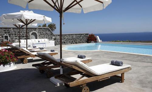 a pool with two lounge chairs and an umbrella at Aghios Artemios Traditional Houses in Imerovigli