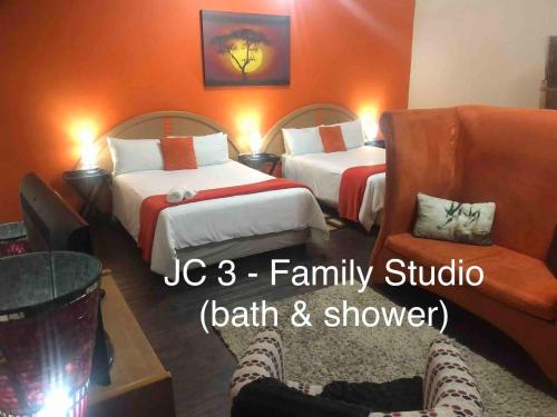 a hotel room with two beds and a chair at JC Studios Ermelo in Ermelo