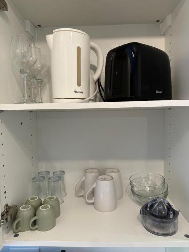 a shelf filled with cups and other kitchen items at LE VEGETAL / Nay centre in Nay