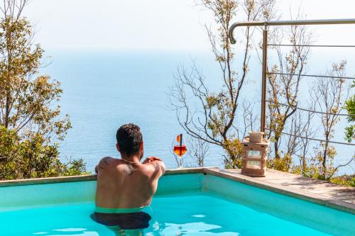 a man in a swimming pool with a glass of wine at Tenuta Delle Ripalte in Capoliveri