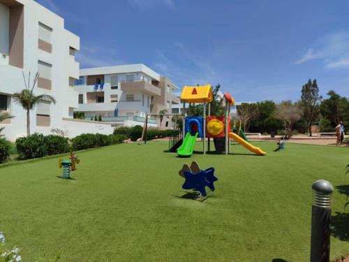 a playground with children playing on a grass field at Appartement avec piscine taghazout imi Ouaddar in Agadir nʼ Aït Sa