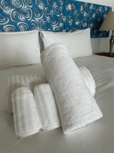 a bed with three white towels on it at Yzerfontein Villa Fantastica - No Loadshedding in Yzerfontein