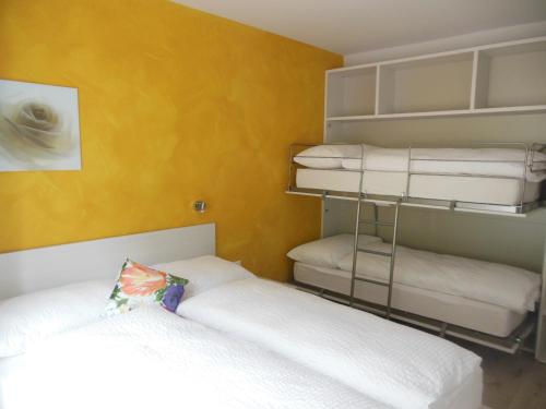 a bedroom with two beds and a yellow wall at B&B Tencia in Prato