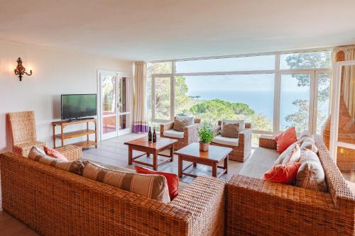 a living room with wicker furniture and a large window at Tenuta Delle Ripalte in Capoliveri