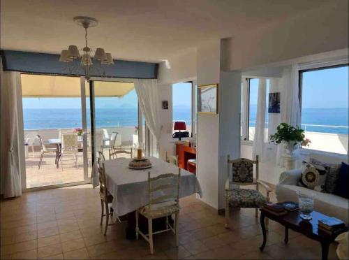 a living room with a table and a view of the ocean at Attico una finestra sulle Isole Eolie in Brolo