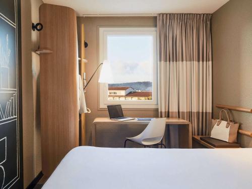 ラ・セーヌ・シュル・メールにあるibis Toulon La Seyne sur Merのベッド、デスク、ノートパソコンが備わるホテルルームです。