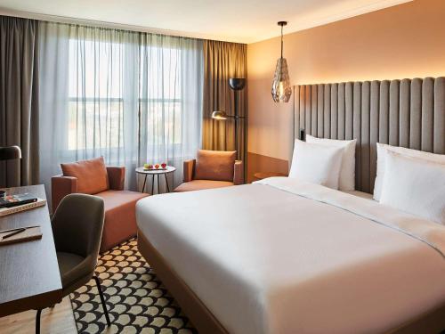 um quarto de hotel com uma cama grande e uma cadeira em Pullman Stuttgart Fontana em Estugarda