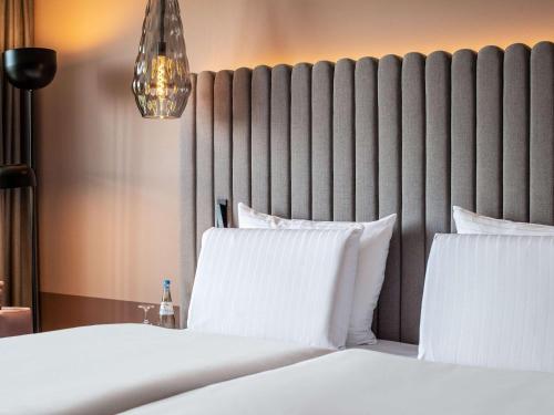 1 dormitorio con 2 camas y almohadas blancas en Pullman Stuttgart Fontana en Stuttgart