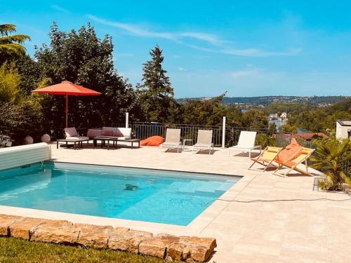 einen Pool mit Stühlen, einem Tisch und einem Sonnenschirm in der Unterkunft La Demeure du Val (piscine, hammam, spa, salle de sport) in Couzon-au-Mont-dʼOr