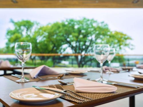 a wooden table with glasses and plates and napkins at Novotel Itu Terras de São José Golf & Resort in Itu