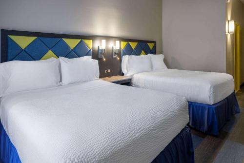 two beds in a hotel room with white sheets at Days Hotel by Wyndham North Bergen in North Bergen