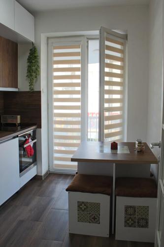a kitchen with a table and some blinds on the windows at Cozy Apartment in Skopje in Skopje