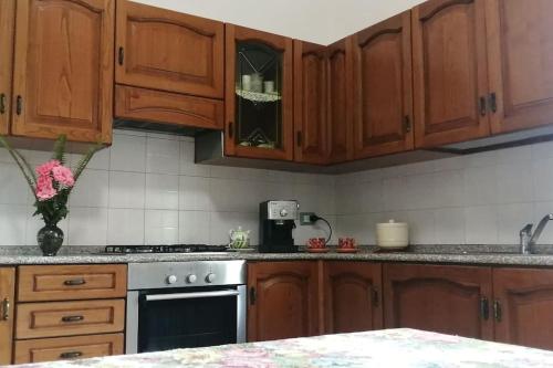 a kitchen with wooden cabinets and a stove top oven at Casa con giardino vicina a Cagliari e aeroporto in Ussana