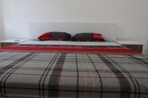 a bed with a plaid blanket and two pillows at Cozy Apartment in Skopje in Skopje