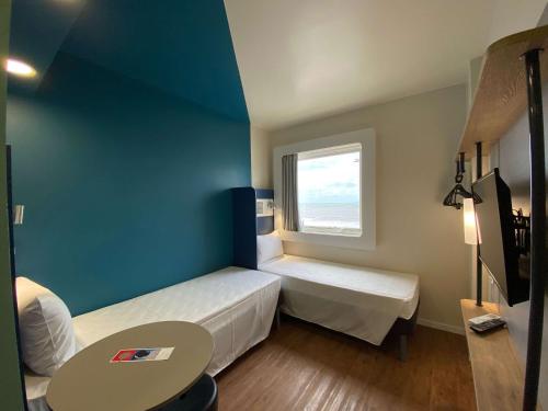 a small room with two beds and a window at ibis budget Recife Jaboatão in Recife