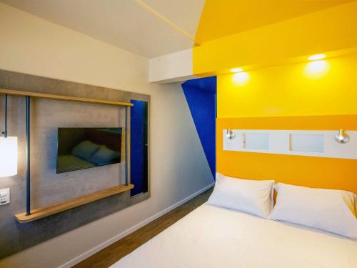 - une chambre dotée d'un lit avec un mur jaune et bleu dans l'établissement ibis budget Recife Jaboatão, à Récife