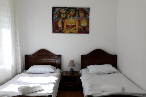 two beds in a room with a painting on the wall at Nadia Guesthouse in Mestia