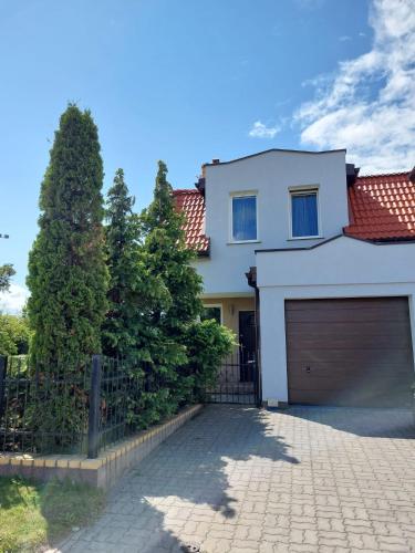a white house with a garage and a fence at Nella in Darłowo
