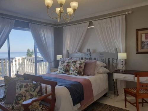 een slaapkamer met een bed, een bureau en een balkon bij C the Sea 3bedroom house with 2 queen and 2 single beds max 6sleep 2bathroom walk distance to beach in Glentana Outeniqua Strand with free Wi-Fi and sea view in Outeniqua Strand