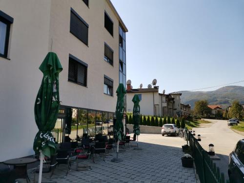 een groep parasols en tafels en stoelen naast een gebouw bij Malena in Goražde