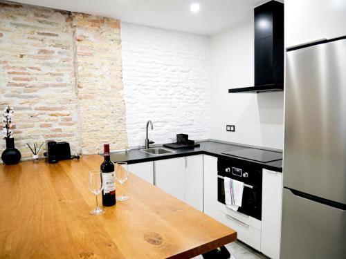 eine Küche mit einem Holztisch mit zwei Weingläsern darauf in der Unterkunft Espacioso apartamento en el centro de Pamplona in Pamplona