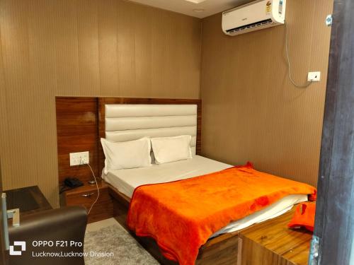 a bedroom with a bed with an orange blanket at HOTEL KBS in Lucknow