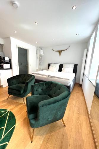 ein Schlafzimmer mit einem Bett und zwei grünen Stühlen in der Unterkunft City Centre Apartment in Nürnberg