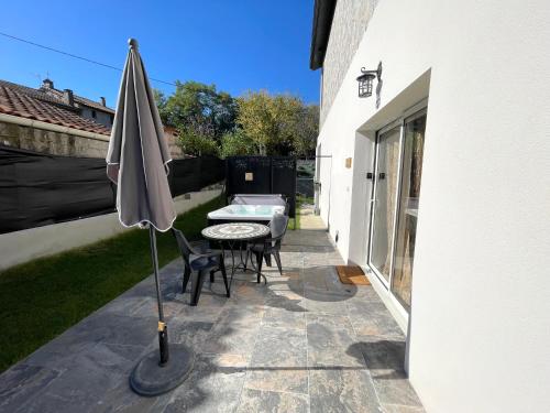 a patio with an umbrella and a table and chairs at Siam Mahanakhon Appart & Spa in Rieux-de-Pelleport