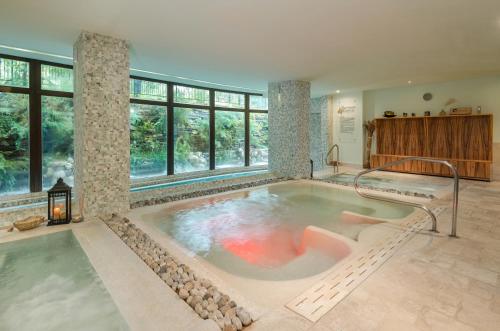 a large bath tub in a room with windows at Ovindoli Park Hotel & SPA in Ovindoli