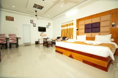a bedroom with a large bed and a living room at Aruna Residency in Sankarankovil