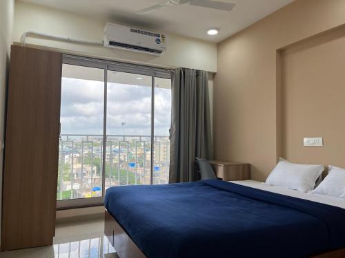 a bedroom with a blue bed and a large window at Juhu Getaway with Rooftop Pad! in Mumbai