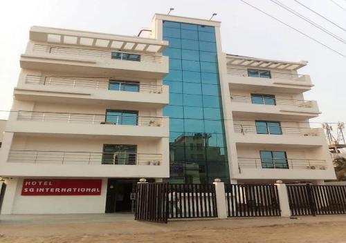 a tall white building with a glass facade at Hotel S G International Danapur in Dānāpur