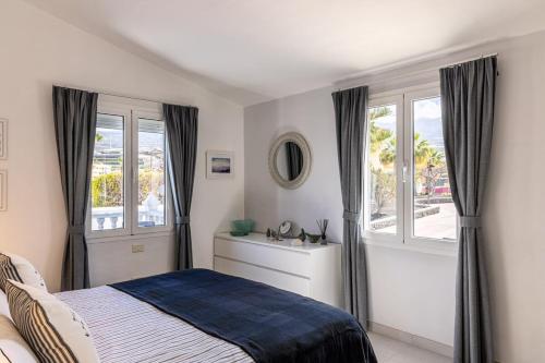 a bedroom with a bed and two windows at A Luxurious Villa On The Island Of Tenerife in Playa de San Juan