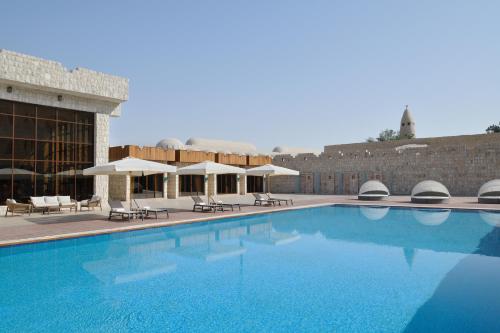 a swimming pool with chairs and umbrellas next to a building at Al Samriya Hotel, Doha, Autograph Collection 